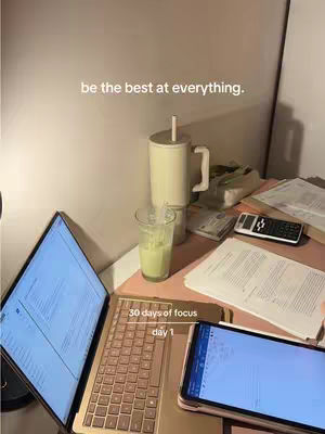 The image shows a workspace setup with a laptop, a tablet, papers, and a drink. The lighting is soft, and the color palette is muted with a focus on neutral tones with touches of green.