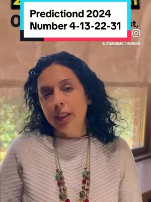 A woman with dark curly hair wearing a cream-colored sweater and a multi-strand necklace is shown in a medium shot from the chest up. The background features a blurred indoor scene with windows. The cover image has a text overlay in a blue and white box.