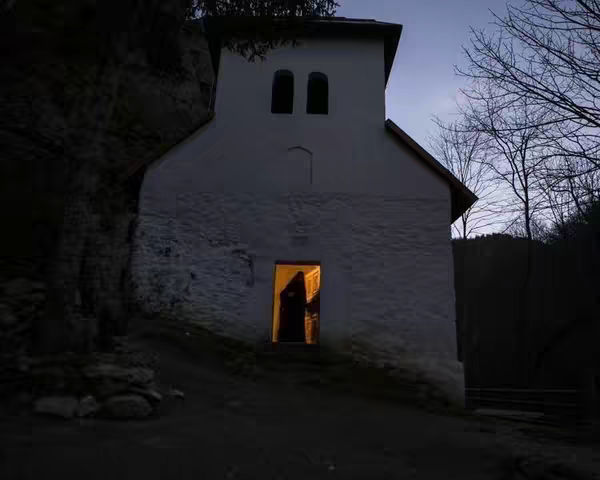 The cover image shows a small, white building with a gabled roof. It features two arched windows and a doorway that's illuminated from within. Shadows and dark terrain surround the building, possibly trees.