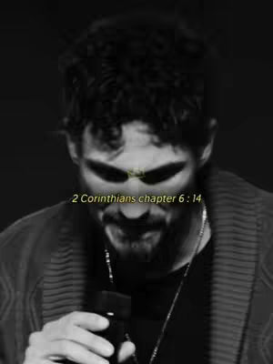A black and white image features a man from the chest up, looking down, with text overlayed. The man has dark, curly hair and is wearing a dark shirt and a blazer. A microphone is visible in his hand. Text at the bottom reads: "2 Corinthians chapter 6: 14", in a light yellow color.
