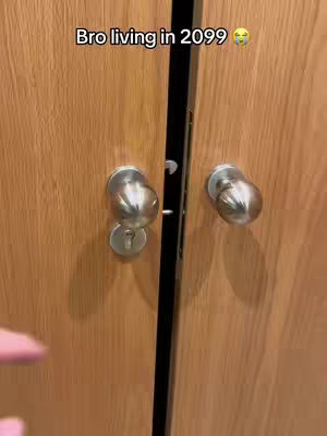 The image shows a close-up of a wooden door with two silver doorknobs. The doorknobs are round with a keyhole on the left side. The door has a black vertical stripe and a text overlay at the top.