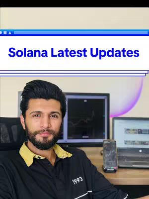 The cover image features a man with a dark beard and hair, wearing a black shirt with a yellow collar. The text overlay states 'Solana Latest Updates' on a blue background. The man is seated and looking at the camera with a serious expression. In the background, there is a computer screen and a mobile phone, with the focus on the desk setup he's sitting at.