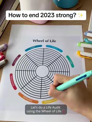 The cover image shows a person's hand writing on a printed 'Wheel of Life' template. The wheel is a circle divided into segments representing different life areas. Text overlays include the title 'How to end 2023 strong?' and the prompt 'Let's do a Life Audit using the Wheel of Life'. The layout is clean and organized, with a wooden surface and colored markers in the background.