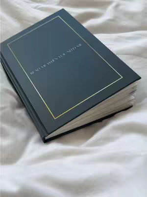 The cover image shows a closed, dark blue book with gold trim, resting on a white, rumpled surface. The book's cover has a gold-bordered rectangle, with the words "READ ME WHEN YOU NEED ME" written in a white, elegant font. The background is textured, with soft shadows and highlights, implying a comfortable setting. The composition focuses on the book, with a slightly angled perspective.
