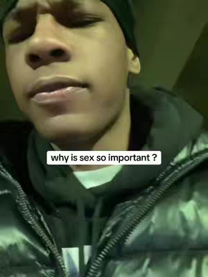 A close-up shot of a young man looking slightly upwards with a neutral expression. He is wearing a black beanie and a puffy black jacket over a black hoodie and a white shirt. The background is dimly lit, and a rectangular white text box is overlayed, containing the question, 'why is sex so important?'. The image is simple but direct.