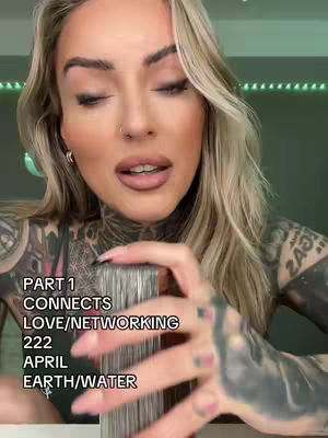 A close-up shot features a woman with long, blonde hair and extensive tattoos on her arms and neck, holding a deck of cards. She is looking towards the camera with a focused expression. Text overlays on the image state 'PART 1 CONNECTS LOVE/NETWORKING 222 APRIL EARTH/WATER'. The background is a muted green.