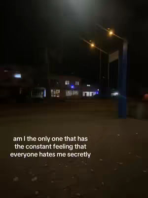 A nighttime scene of a street with buildings in the background. The street is empty, with streetlights illuminating the area. Text overlayed on the image poses a question about feeling hated.