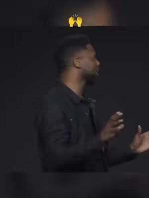 A man in a black jacket is speaking, the background is dark. The graphic shows two hands clapping above his head.