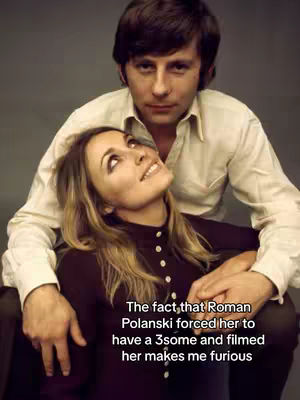 The image shows what appears to be a vintage photograph of a man and a woman. The man, in a white button-down shirt, is positioned behind the woman. The woman, with blonde hair, is looking up with a slight smile and wears a dark button-down blouse. The background appears to be plain gray.