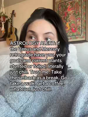A selfie-style image shows a woman with dark hair framed by a wall with artwork and a guitar, positioned in front of an off-white background, with text overlay on top. The woman is facing the camera directly.