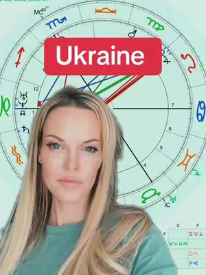 A woman with long blonde hair is positioned in front of a circular astrology chart. A red banner, labeled "Ukraine", is placed over the center of the chart. The woman looks directly at the viewer with a composed expression. The background is a mint green color, and there are astrological symbols and lines in the chart.