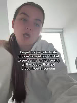 A selfie-style video with the creator in the foreground, slightly angled with a neutral expression. The background is out of focus, with a window visible. Text is overlaid on the video, expressing regret about a ticket.