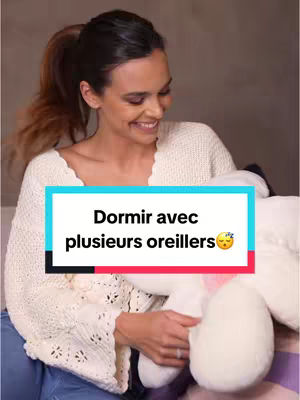 A woman with dark hair in a high ponytail smiles. She wears a white sweater and holds a large white pillow, with a text box overlay in the center.