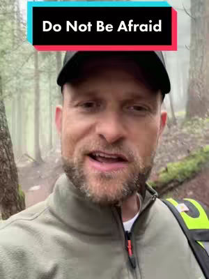 A man in a green jacket and a black cap is the focus, seen from the chest up. The backdrop features a blurry forest, evoking a sense of nature. Text overlayed is a call for the viewer to not be afraid.