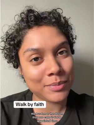 A close-up shot of a woman with short, curly hair, looking slightly upwards with a soft expression. She's wearing a black top, and the background is a neutral, off-white color. Text overlays, 'Walk by faith' and supportive text are present.