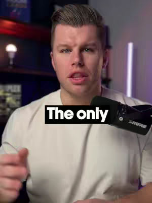 A close-up shot of a man speaking into a microphone. He is wearing a white t-shirt. A black box with white text overlays in the center of the image.