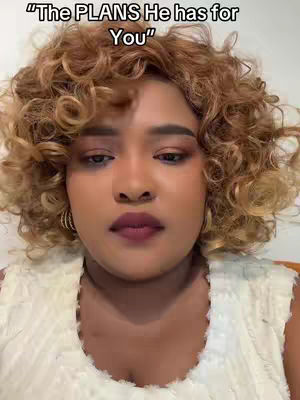 A close-up shot of a woman with curly blonde hair and dark makeup looking down. Text overlays the image.