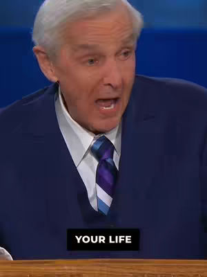 A man in a blue suit with a white shirt and striped tie is speaking with his mouth open. At the bottom of the image, there is a black box that says 'YOUR LIFE'