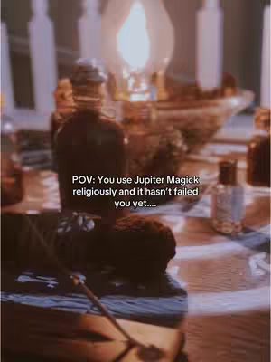 A dimly lit scene with ritual objects and glowing candles. In the foreground, a dark bottle stands prominently with a label and appears to be the central focus of the composition. Beside the bottle, is a dark-colored book with a wand. In the background, additional candles and a dimly lit lamp create a warm, mystical ambiance.