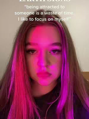 A close-up shot of a young woman's face, with her expression focused and a slight pout to her lips. The lighting is dramatic, with bright pink and purple hues illuminating the sides of her face and hair, creating a stark contrast against a dark background. Text overlayed on the image quotes a perspective on relationships.