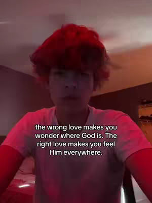A young man with red hair is centered in the frame, viewed from the chest up. He faces the camera with a neutral expression, set against a dimly lit background. The text overlay offers a message about love.