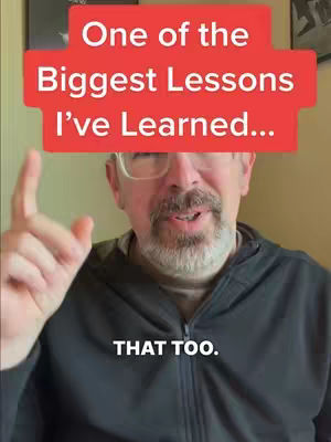 A middle-aged man with glasses, a short beard, and a dark jacket is speaking. A red rectangle with white text at the top of the frame states, "One of the Biggest Lessons I've Learned...". Another white text box at the bottom says "THAT TOO."
