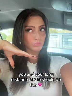 The cover image shows a woman inside a car, angled from a selfie perspective. She's looking upwards with a thoughtful expression, her hand positioned near her face. Text overlayed at the bottom states, 'you and your long distance bestie should do this', along with a pink heart emoji. The background suggests an outdoor environment, possibly a parking lot or street, visible through the car windows.
