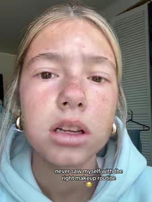 A close-up shot of a young woman with blond hair and hoop earrings. She is looking slightly down with a neutral expression, and text overlayed at the bottom of the image.