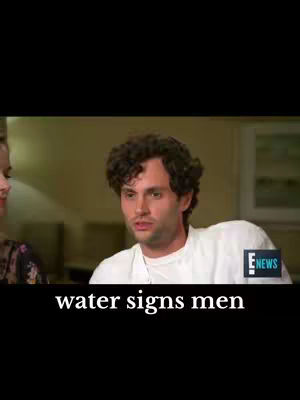 A medium shot of a man with curly brown hair, slightly to the right of the frame. He is wearing a white shirt and appears to be in an interview setting. A text overlay at the bottom reads "water signs men". The background is blurred, suggesting an interior space.
