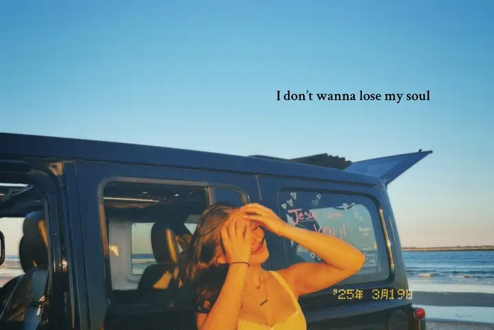 A woman stands with her arms up in front of a black jeep with a beach and blue sky in the background. Text overlayed on the image.