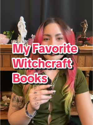 A medium shot shows a woman centered in the frame, holding a small object, with text overlayed. Her hair is styled with pink and yellow highlights. The background is a dark wooden cabinet adorned with decorative items and statues.