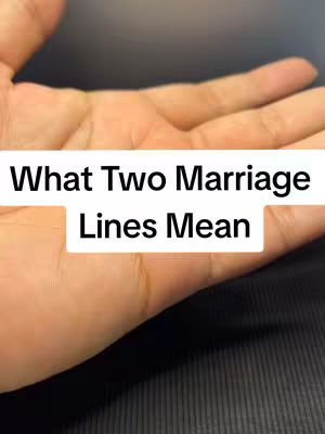 The image shows a close-up of a person's palm facing upwards. Above the palm and slightly obscuring it is a white rectangular text box with the words 'What Two Marriage Lines Mean' in black text.