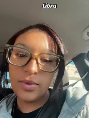 A selfie taken from inside a car. The main subject is a person wearing glasses. The background includes car parts and a glimpse of the outdoors. There is a text overlay that says Libra.