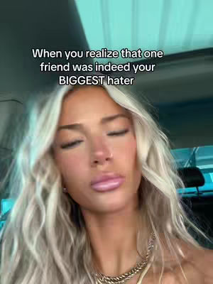A close-up shot featuring a fair-skinned woman with long, wavy blonde hair and a diamond necklace. She has her eyes closed and her lips slightly parted, angled slightly towards the left, with a blurred turquoise background visible.