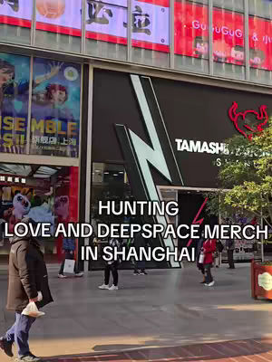 A street scene in Shanghai featuring a store entrance with the text 'TAMASHII NATIONS' and various storefronts with signs and advertisements in the background. A text overlay promotes 'HUNTING LOVE AND DEEPSPACE MERCH IN SHANGHAI.'