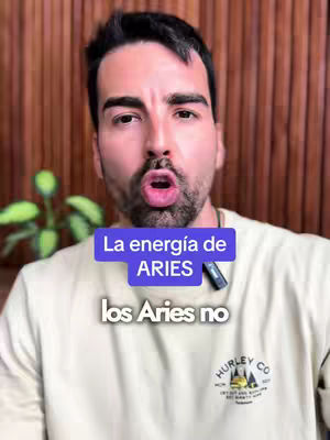 A man with dark hair and a beard is looking directly at the camera with his mouth open with overlay text that reads 'La energía de ARIES' and 'los Aries no'. A wooden panel is in the background, and a plant is to the left.