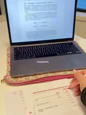 The cover image shows a laptop open on a desk with study materials. A hand is holding a pen, pointing to a paper with notes. The word "consistent" is added as a text overlay.
