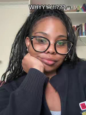 A selfie-style image featuring a woman with dark hair and glasses, looking directly at the camera with a slight, thoughtful expression. She is resting her chin on her hand, and the background is a blurred interior with shelves and books. The top of the image has a text overlay.