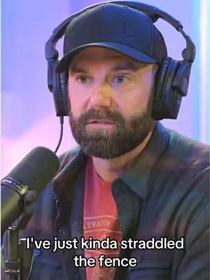 A medium shot features a man wearing a black baseball cap, large headphones, and a dark jacket over a red t-shirt. He's in a setting with indistinct purple and blue lighting. A microphone is positioned to his left, and the overlayed text indicates a quote.