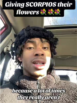 A young Black man is seen from the chest up, inside a car, likely the driver's seat. He has short dark hair under a black headband. The hook text 'Giving SCORPIOS their flowers' is displayed above, and text along the bottom that says 'because a lot of times they really aren't'. The background is blurred but suggests a city environment with daylight visible through the windshield.