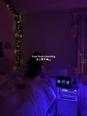 A dimly lit room at night, possibly a bedroom, with a bed in the foreground with blue sheets. The video focuses on somebody in the bed with a digital clock to the right. Text overlayed over the image indicates the time of the video.