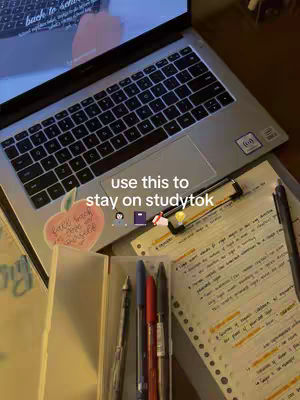 The image shows a workspace with a laptop, notebook, and pens, a sticker with a pink apple on it. The hook text says, "use this to stay on studytok." The scene is well-lit, with a focus on study materials.