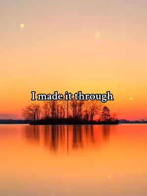 The image depicts a serene landscape. An island with trees is centered in the frame, reflecting perfectly in the still water below. The sky transitions from deep orange to yellow, with a few faint white dots that may represent stars or distant lights. The overall composition is symmetrical and visually calming.