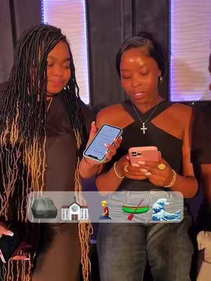 Two Black women are positioned in front of a dark background, holding smartphones. An emoji overlay at the bottom features a rock, a church, a person kneeling, a boat, and a wave. The women appear to be inside a venue with window-like features and a purple lighting arrangement. One woman has long, braided hair, and the other, wearing a black top, has short hair and a necklace with a cross.