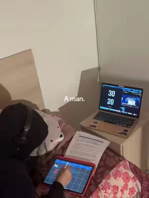 The cover image shows a person, likely a student, studying in bed. They are wearing a hoodie and headphones, with a tablet and open laptop visible on their bed. The room has a simple design, with a bed against the wall and a nightstand next to the bed. There also appears to be a stuffed animal plushie on the bed.