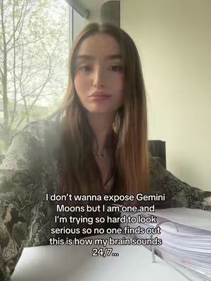 A woman with long brown hair is seated in front of a window, looking directly at the camera with a thoughtful expression. She's wearing a patterned top, and a small necklace. Text is overlaid on the image.