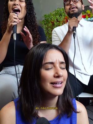 The cover image presents a brightly lit scene with three people, presumably singers, in front of a soft-focus green backdrop. A woman in the immediate foreground has her eyes closed and mouth open while singing into a microphone. Another woman, with curly hair, is on the left, singing. A man with glasses and a beanie is positioned on the right of the image, also singing. Text overlay appears at the bottom.