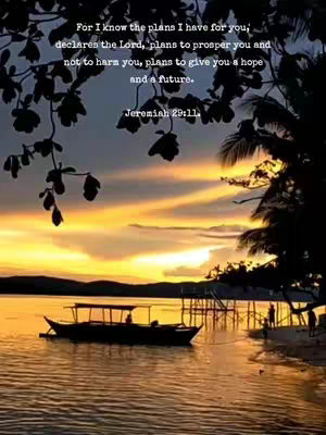A sunset scene over a body of water with a boat in the center. The sky transitions from orange to yellow with dark blue and purple hues. Silhouetted branches frame the top, and a verse is overlaid on the image. The foreground shows the silhouette of a boat with a covered top, and figures are seen on the shore, suggesting a peaceful, reflective setting.