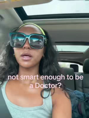 A woman with dark curly hair and large sunglasses sits in a car. The background shows the car interior with a sunroof, and the foreground features the woman's face, with overlaid text.