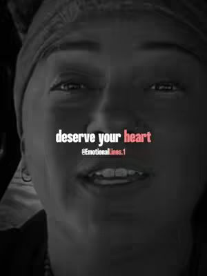 A black and white selfie focuses on a person's face, with text overlayed. The person faces the camera with a slight smile, their eyes looking directly at the viewer. The background is dark and blurry, placing the emphasis on the person’s face. The text, in a bold, white font with pink accents, is centered over the person and reads, “deserve your heart,” followed by the username @EmotionalLines.1.